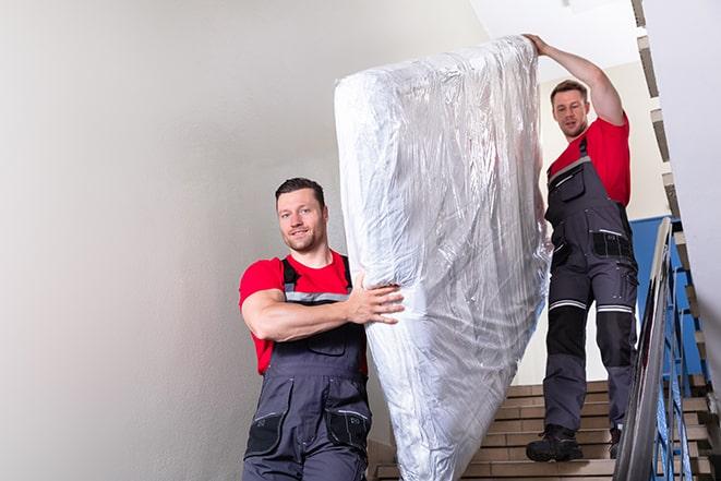 two people carrying a box spring out of a bedroom in Barrington, NJ